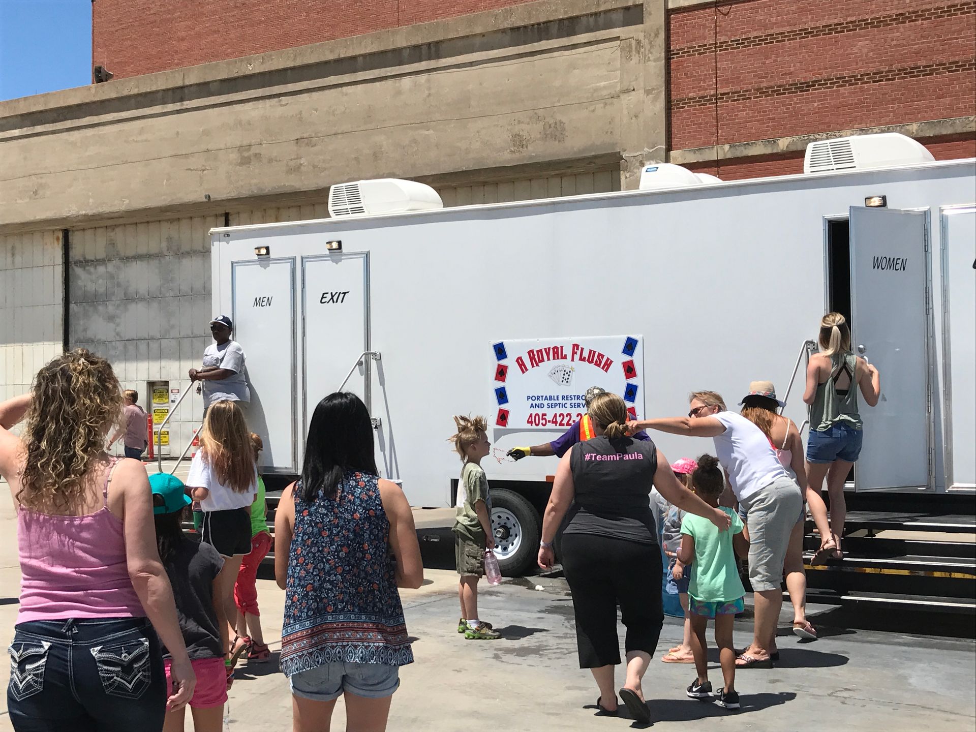 People line up for portable restrooms outside a building.