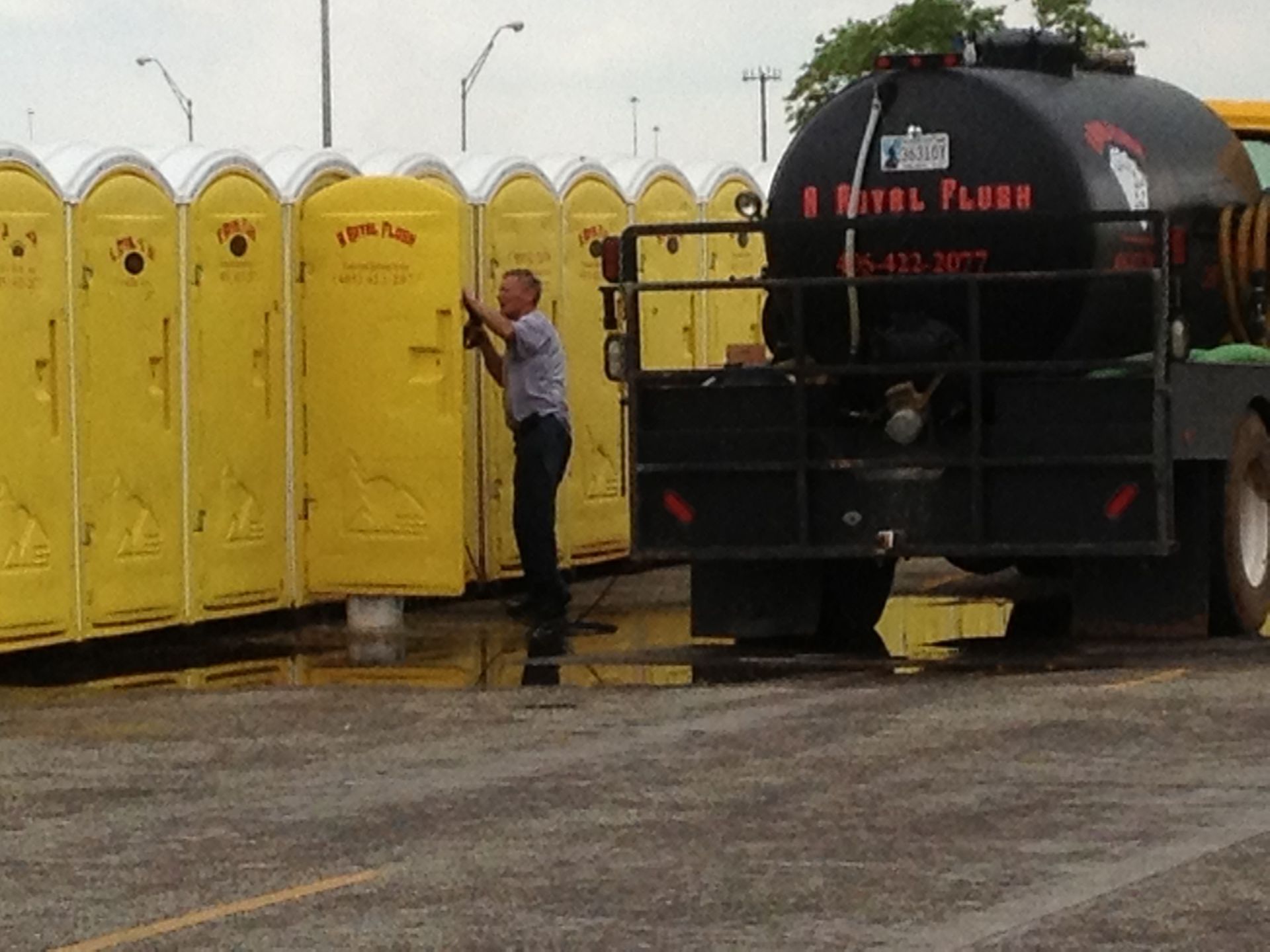 Man cleaning yellow portable toilets with a truck labeled 