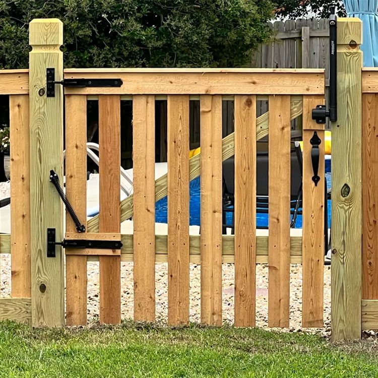 A wooden fence with a gate in front of a pool