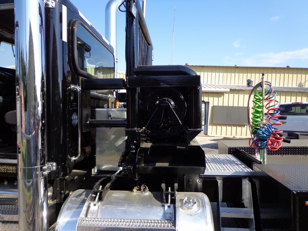 Side view of a semi-truck cab showing a black storage box mounted behind the driver's door above a silver fuel tank.