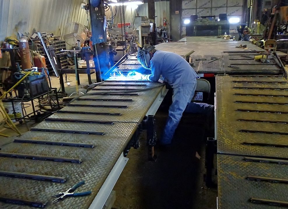 Worker welding metal on an assembly line in an industrial workshop, bright blue sparks visible