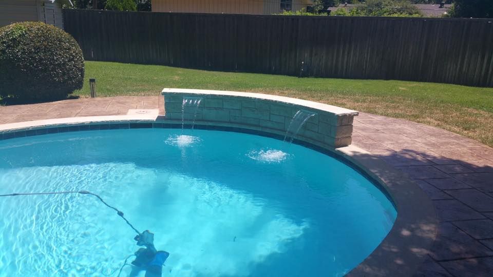 A swimming pool with a waterfall in the middle of it.