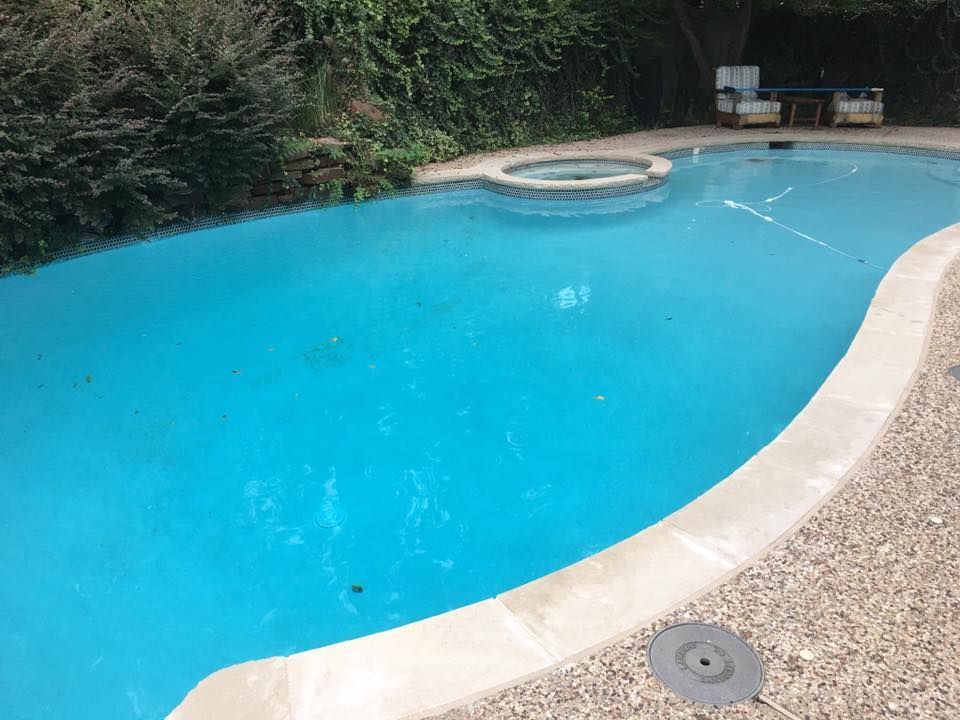 A large swimming pool with a hot tub in the middle of it.