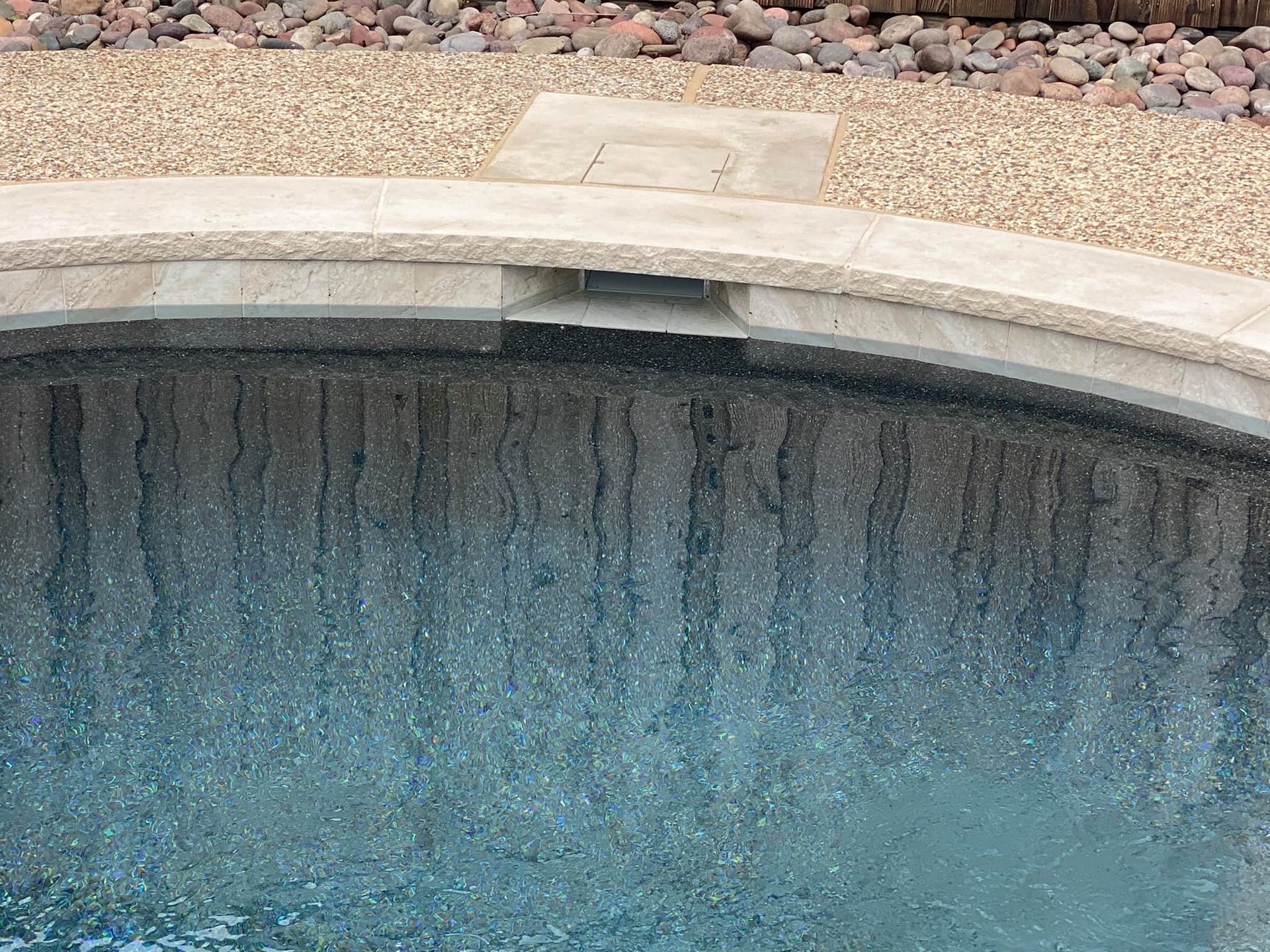 A swimming pool with a fountain in the middle of it