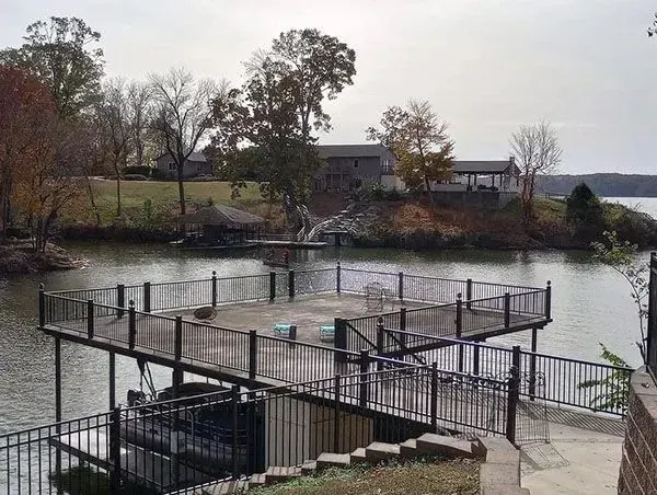 Riverside dock with black railings and stairs overlooking calm water and autumn trees