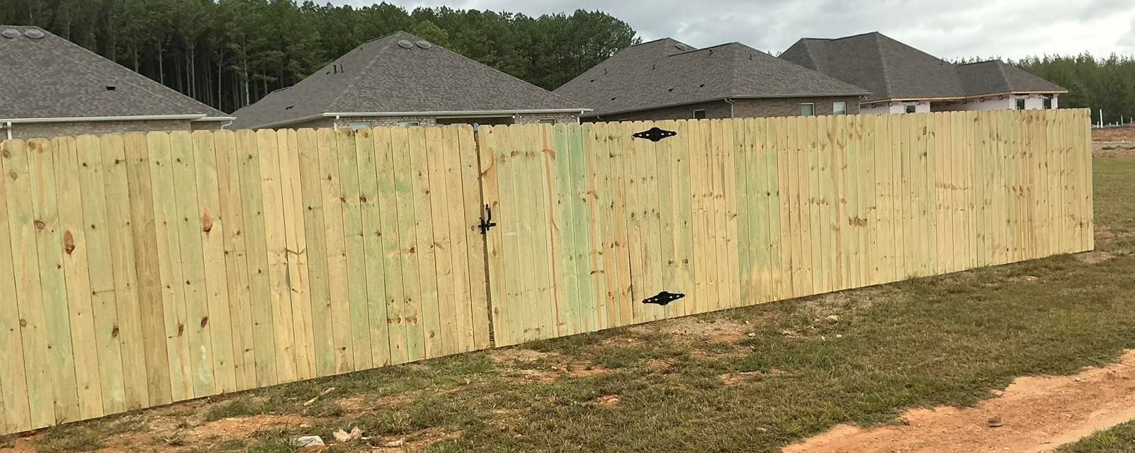 Weathered wooden fence along a suburban yard with rooftops in the background