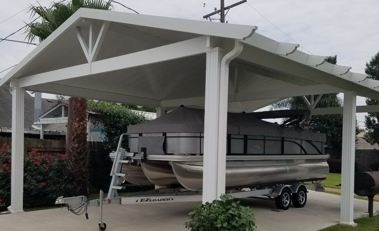 White carport sheltering a pontoon boat on a trailer, parked on a concrete driveway. Cloudy day.