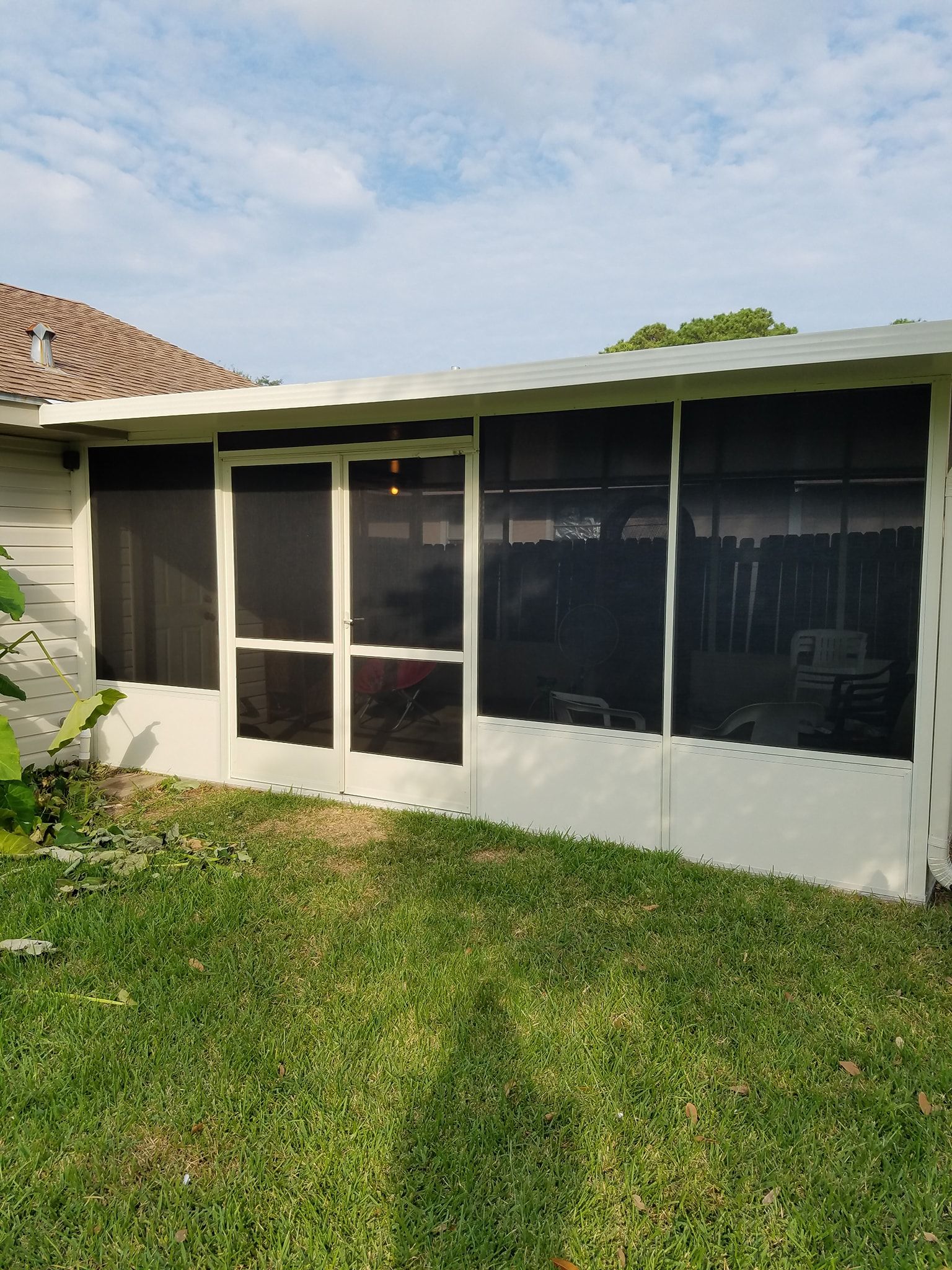 White screen enclosure with black screens on a grassy lawn.