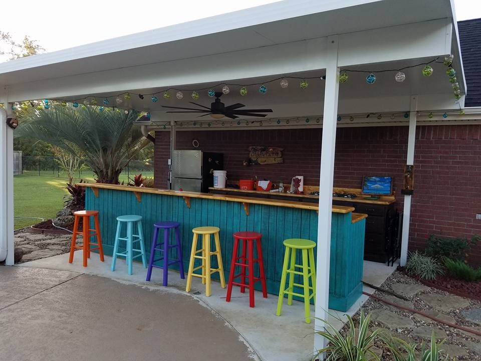 Outdoor bar with colorful stools and hanging lights.