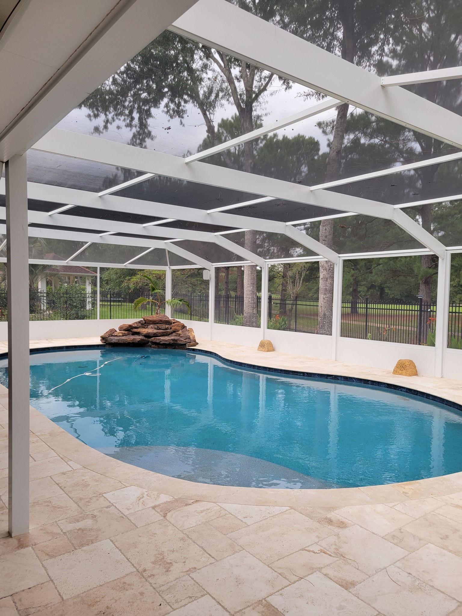 Pool area with white screened enclosure and clear blue water.