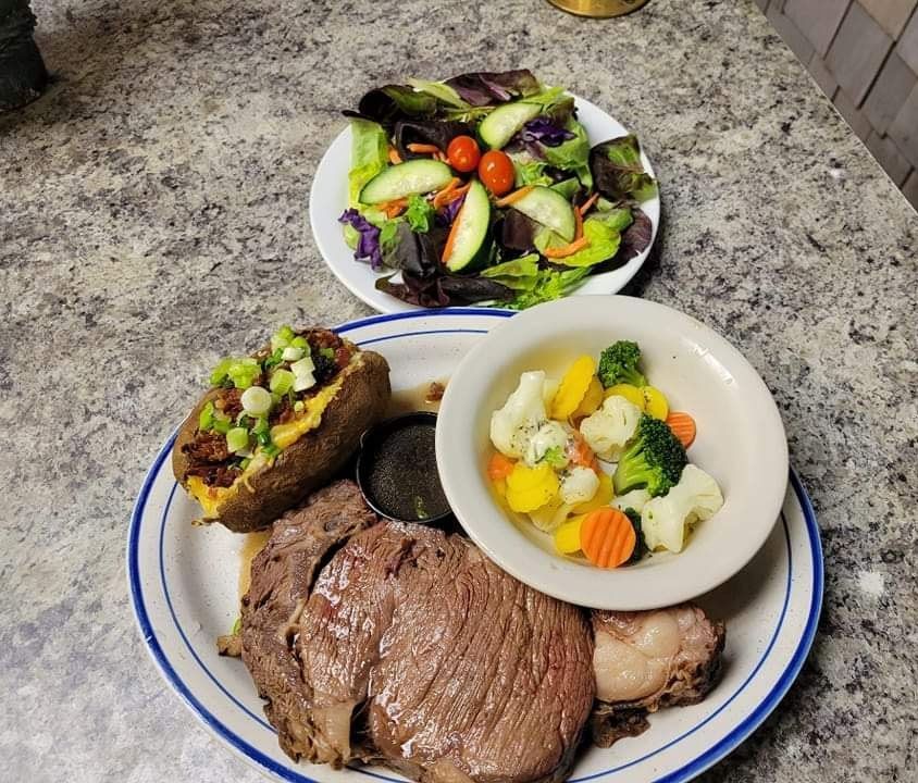 A plate of food with a steak and vegetables on a table.