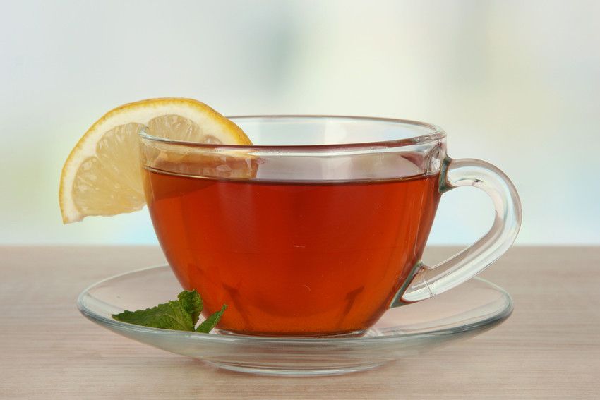 A cup of tea with a slice of lemon on a saucer on a table.
