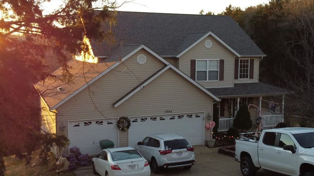 Suburban house with three cars parked in the driveway at sunset, fire glowing behind the trees on the left