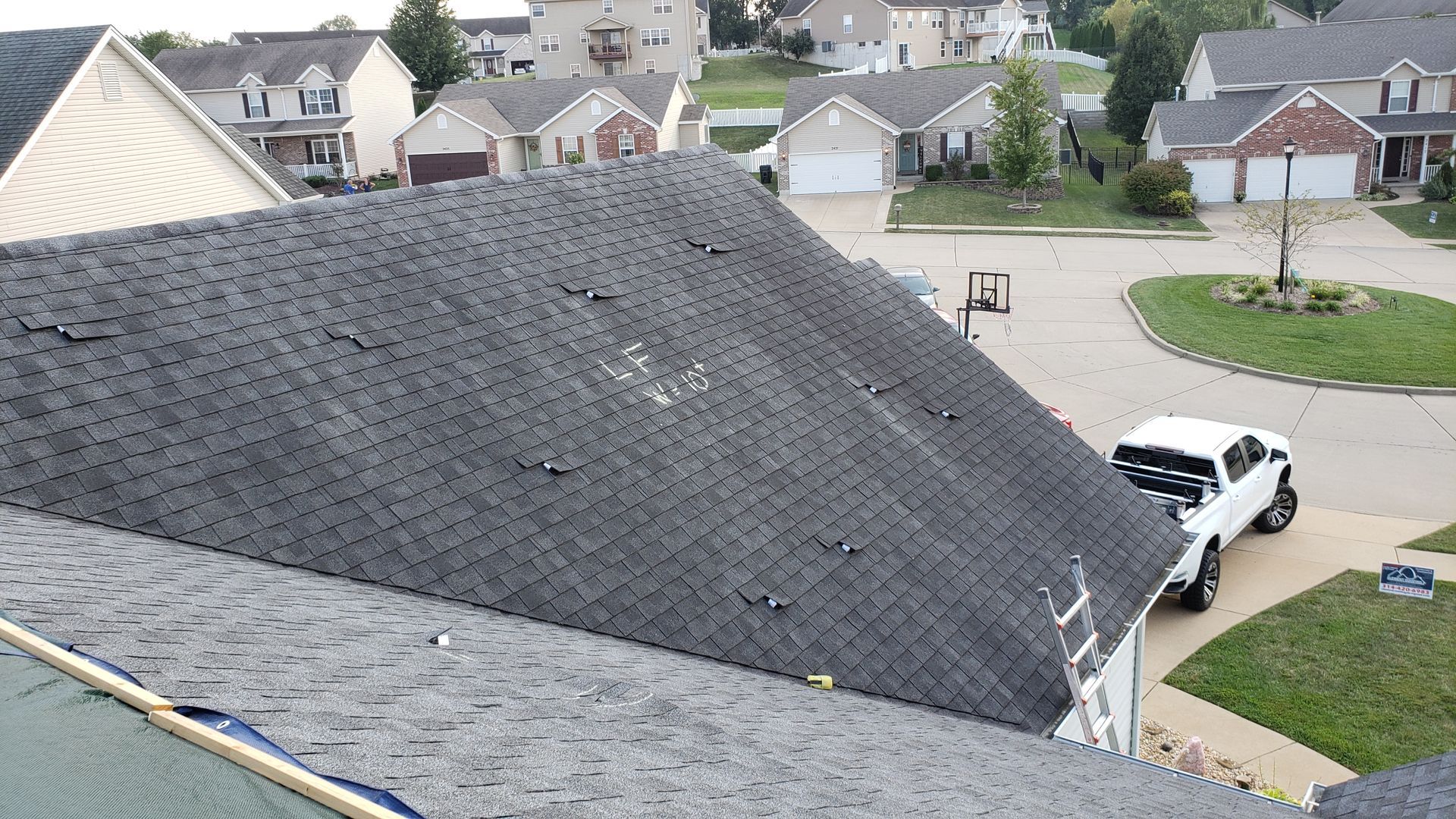 View from a roof over a suburban neighborhood, with a white SUV parked below.