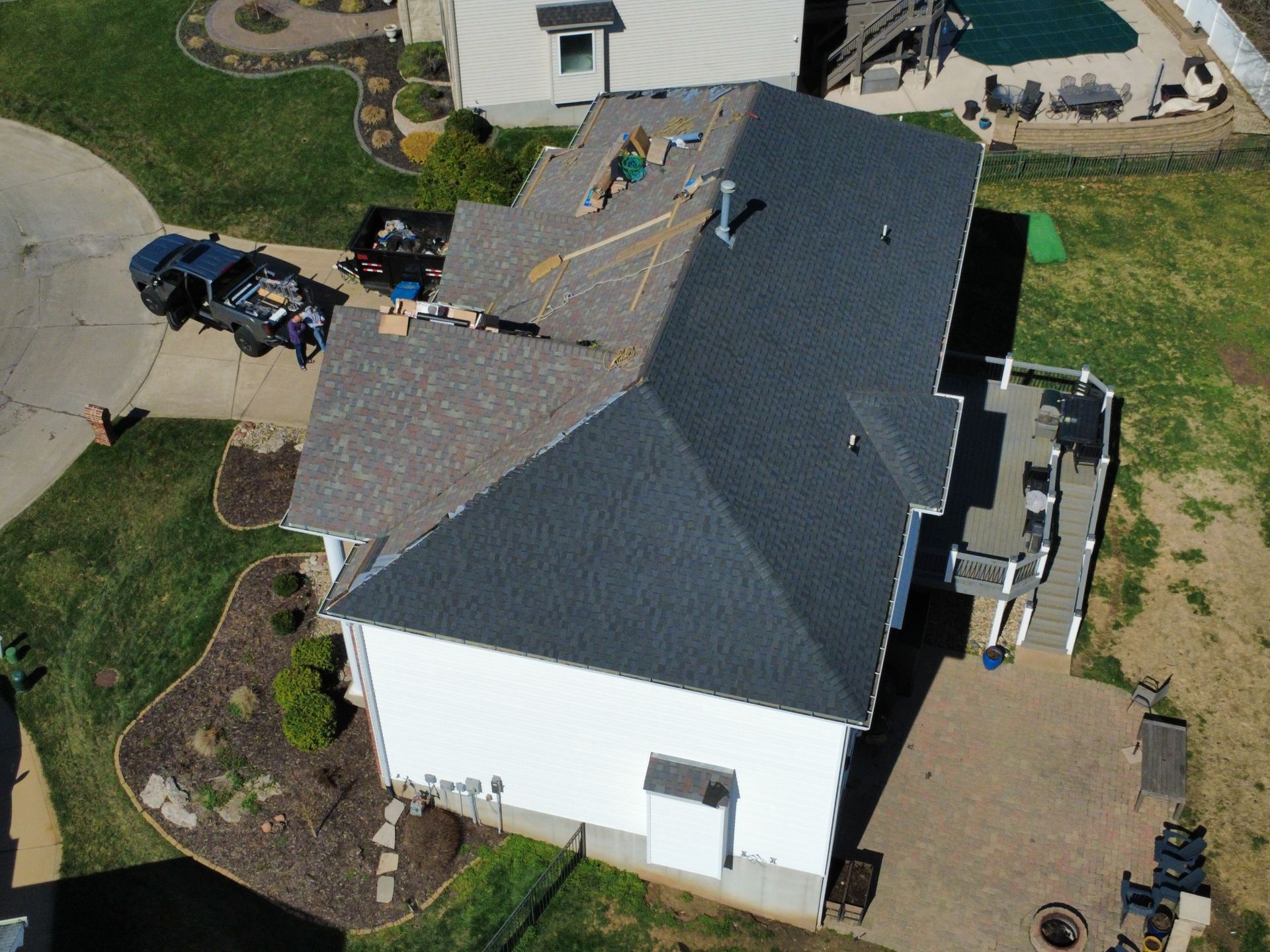 Aerial view of a white house with a dark gray roof, driveway, and landscaped yard.