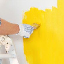 Man painting a wall with yellow paint