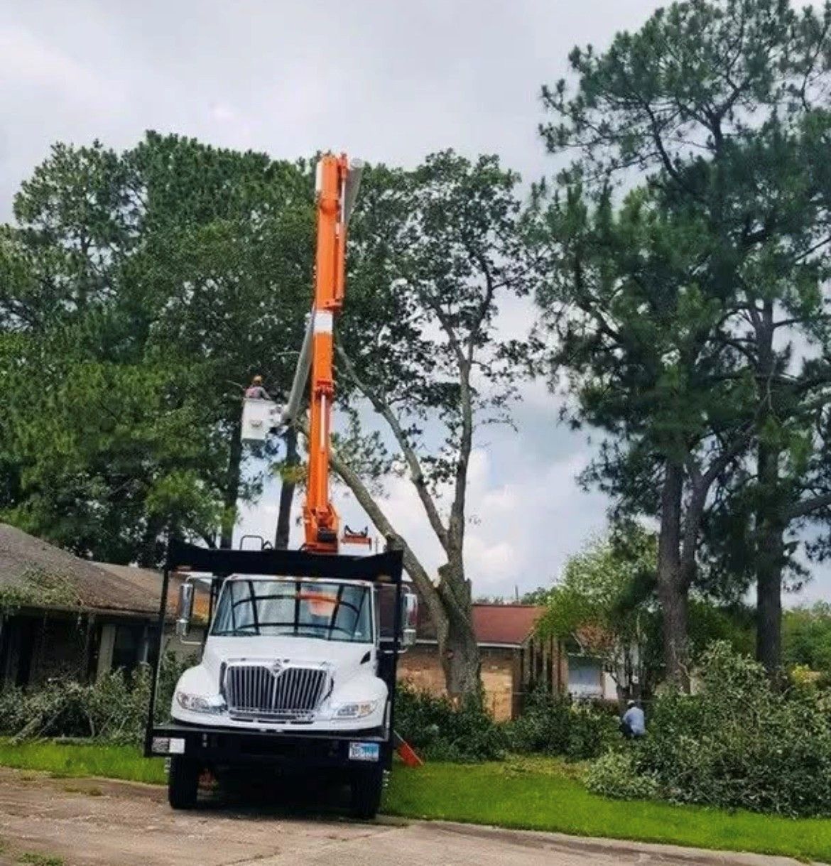 A white truck with a crane on the back is parked in front of a house.