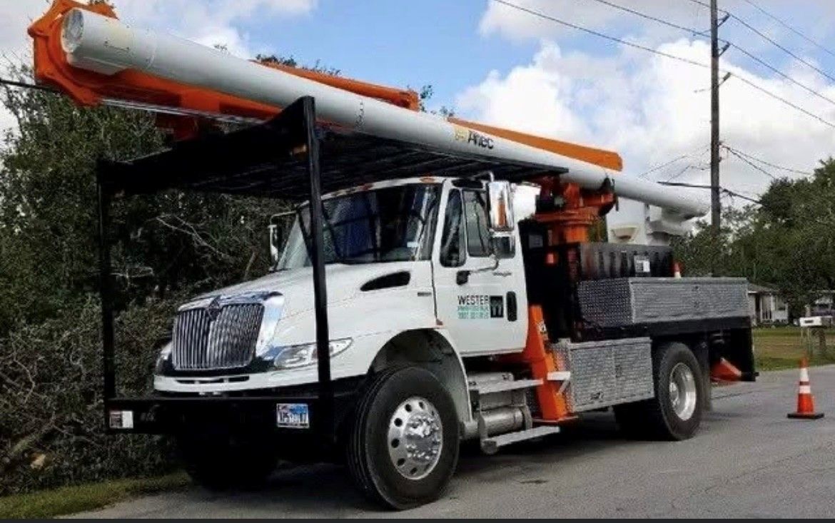 A white truck with a crane on the back is parked on the side of the road.