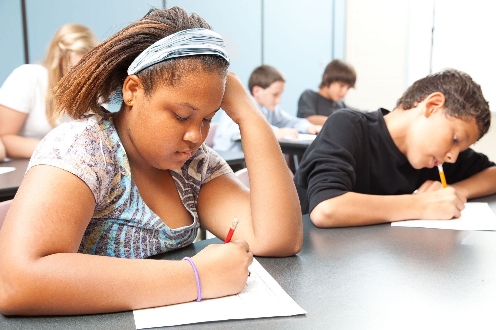 Students writing at desks during a classroom test, focused and quiet