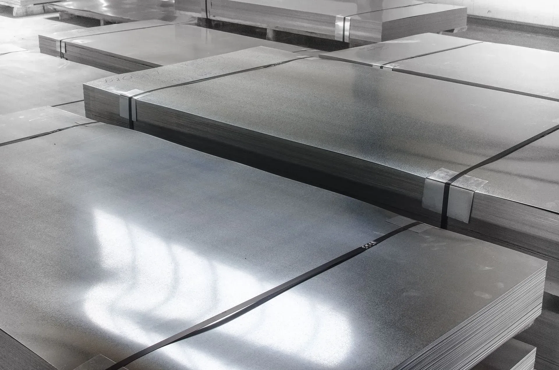 Stacks of reflective silver metal sheets in an industrial storage area