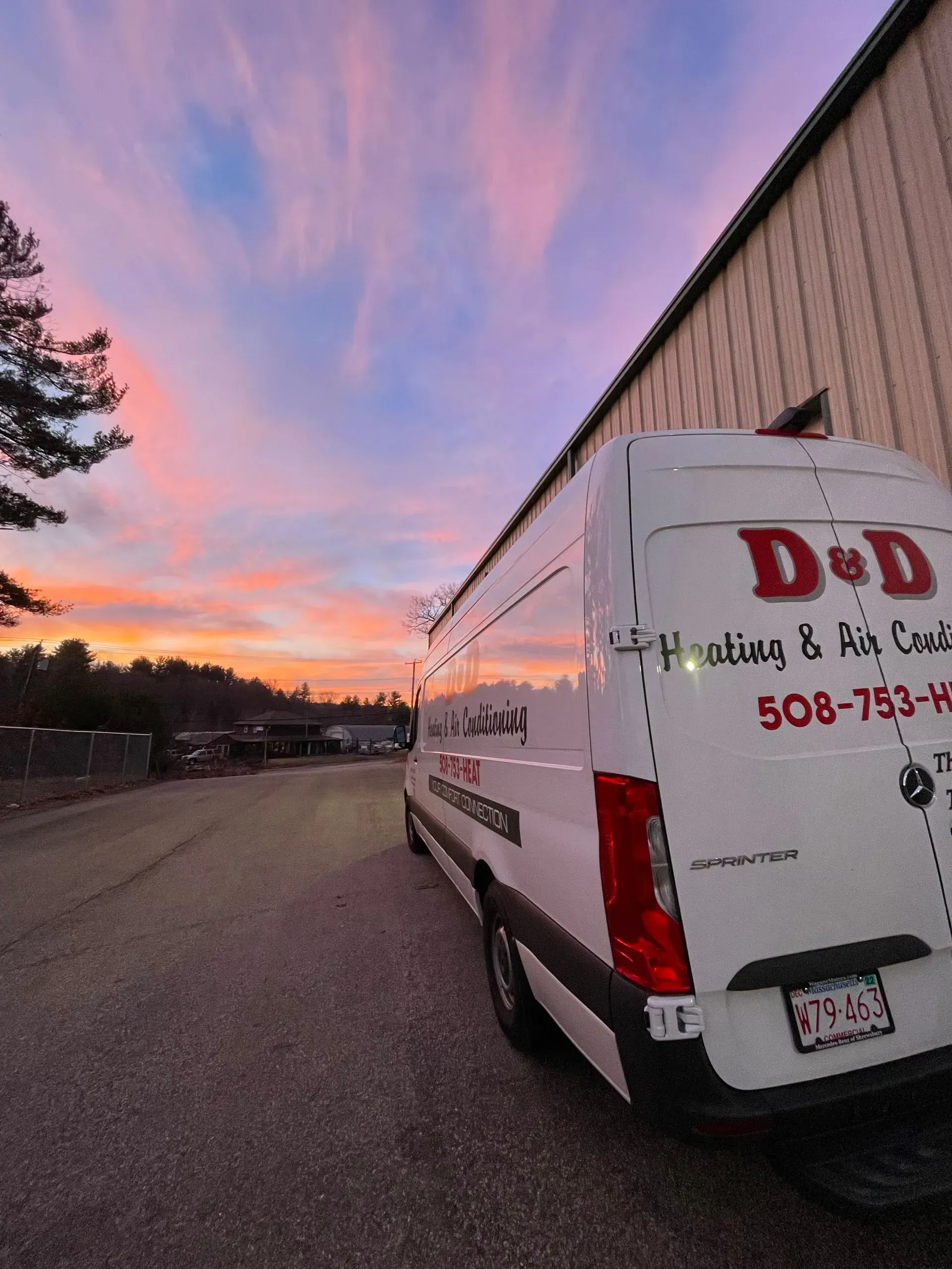 White D&D delivery van at sunset on a road, with pink sky and trees in the background