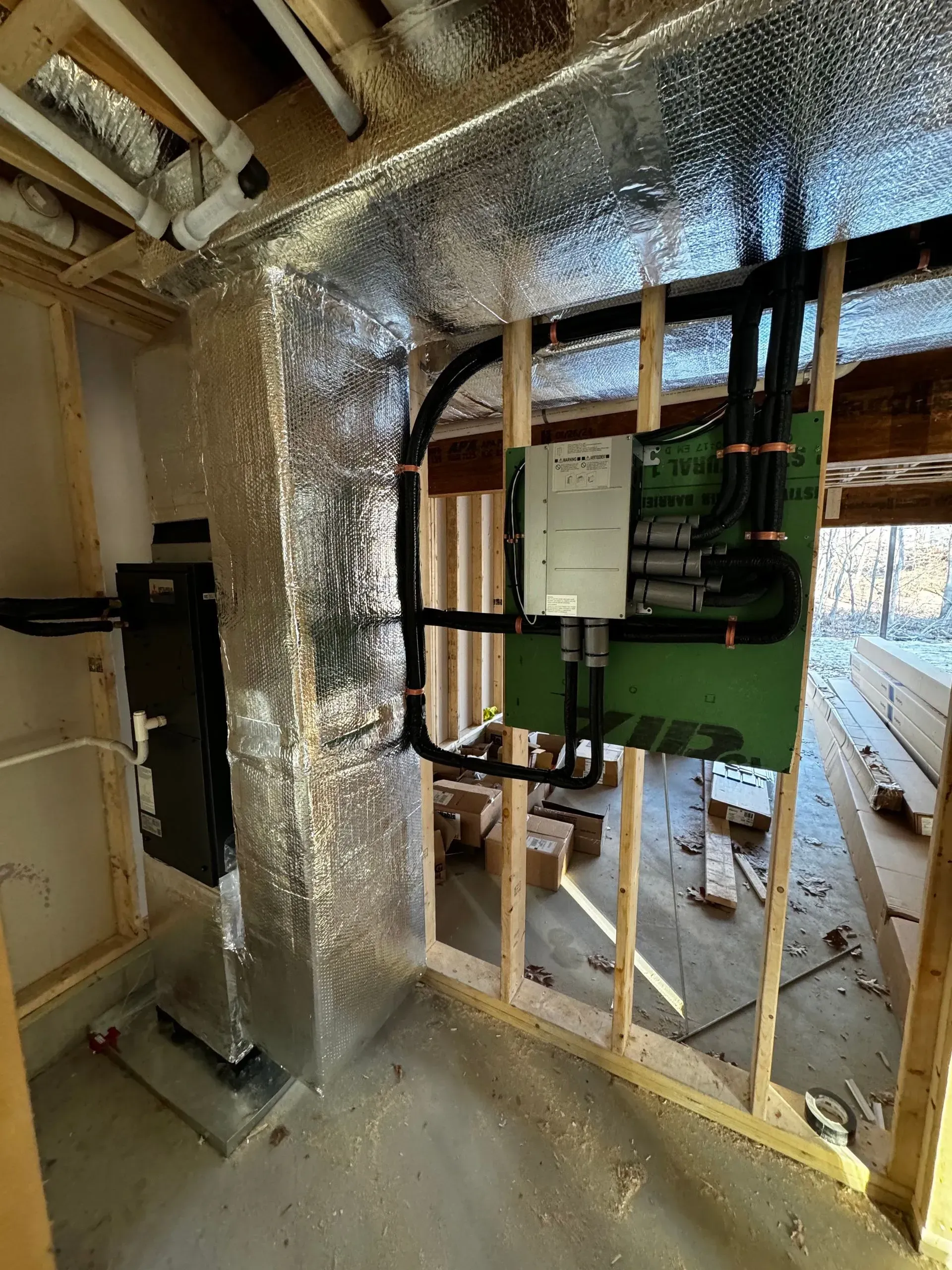Damaged interior wall with exposed insulation, framing, and electrical panel during renovation
