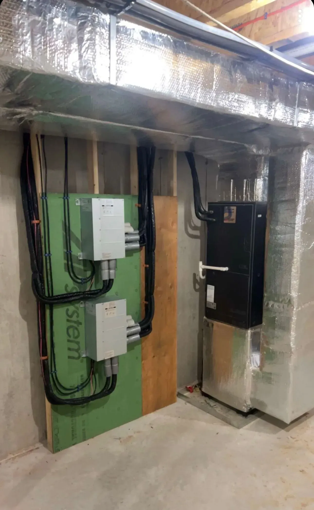 Industrial utility room with insulated ducts, electrical panels, and green wall-mounted equipment.