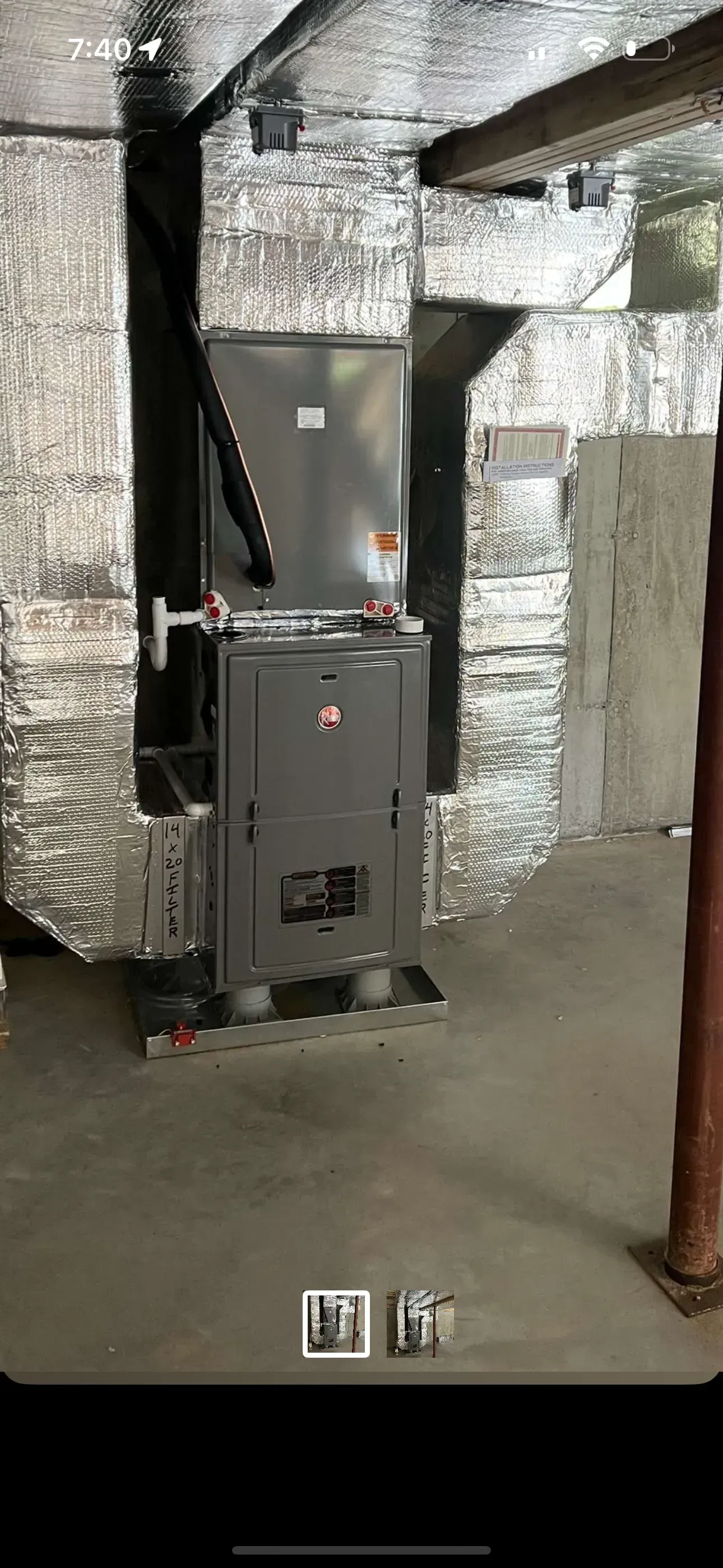 Silver-wrapped HVAC furnace in a utility room with exposed ductwork and concrete floor.