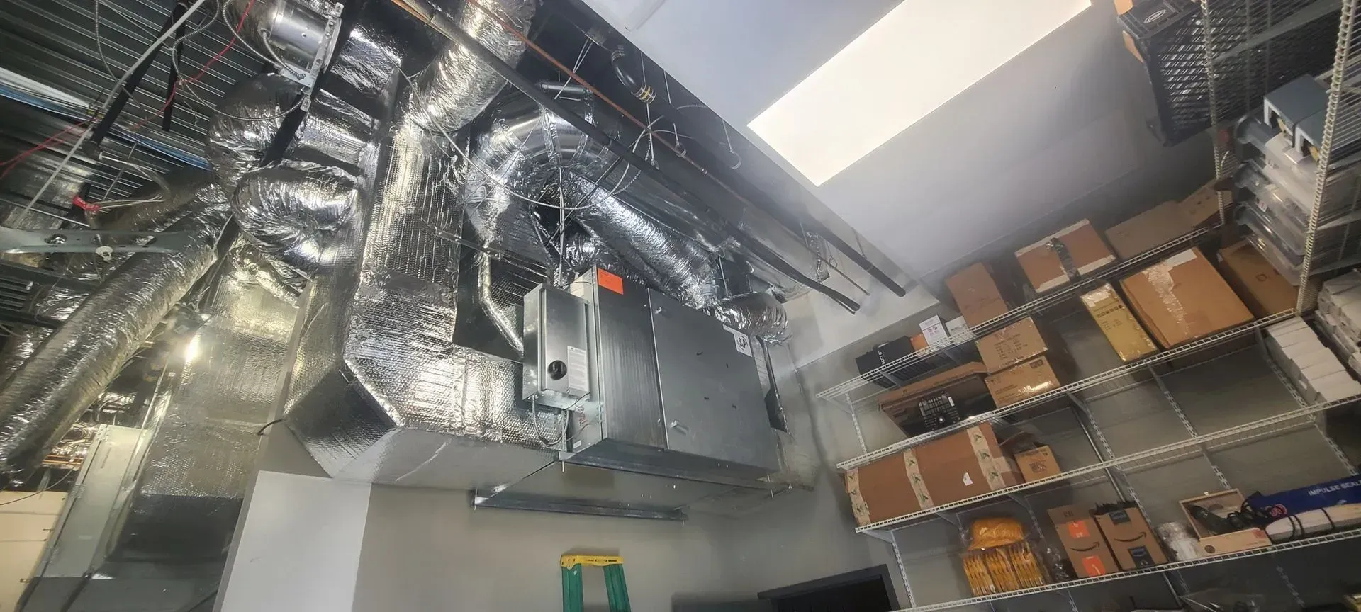 Industrial ceiling with large silver HVAC ducts and exposed metal framing in a warehouse-like interior