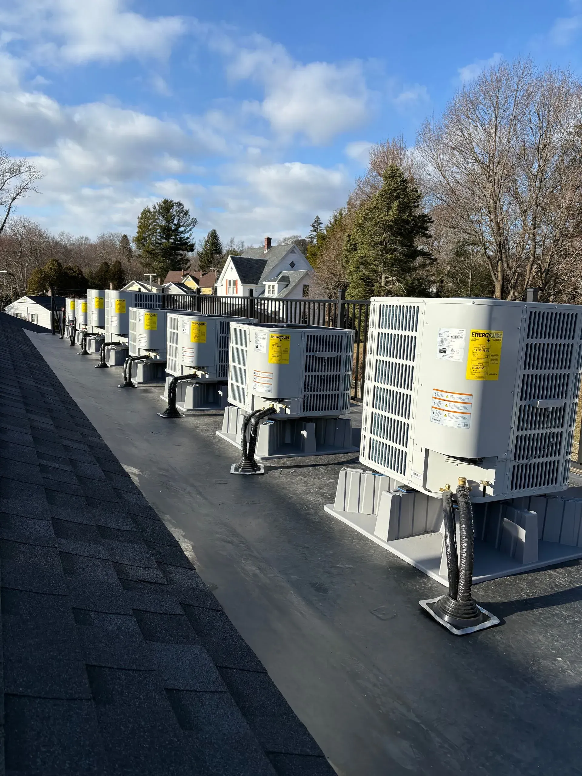 Row of rooftop HVAC units on a flat roof under a blue sky