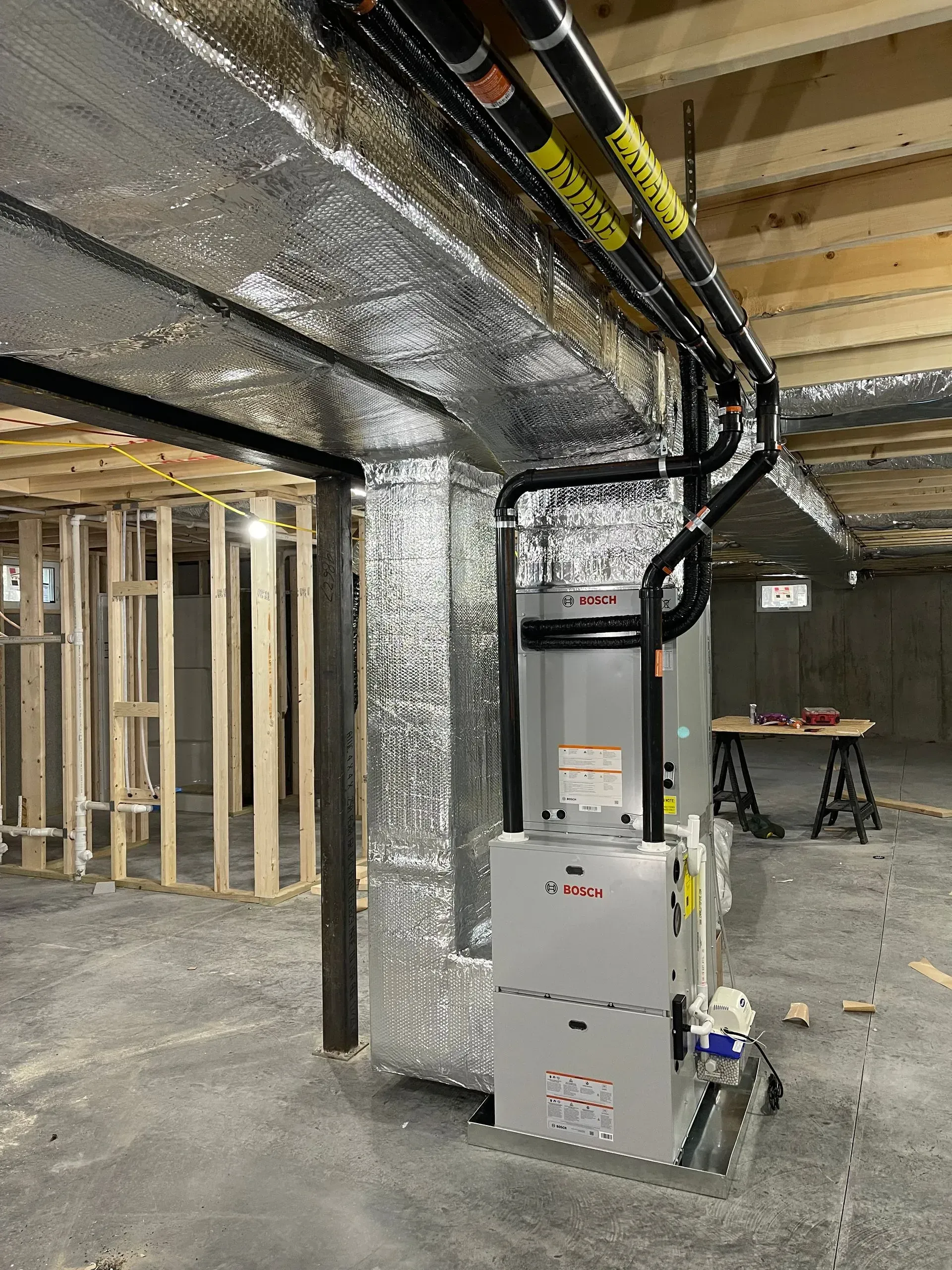 Basement utility room with HVAC furnace, exposed joists, and electrical/ductwork overhead