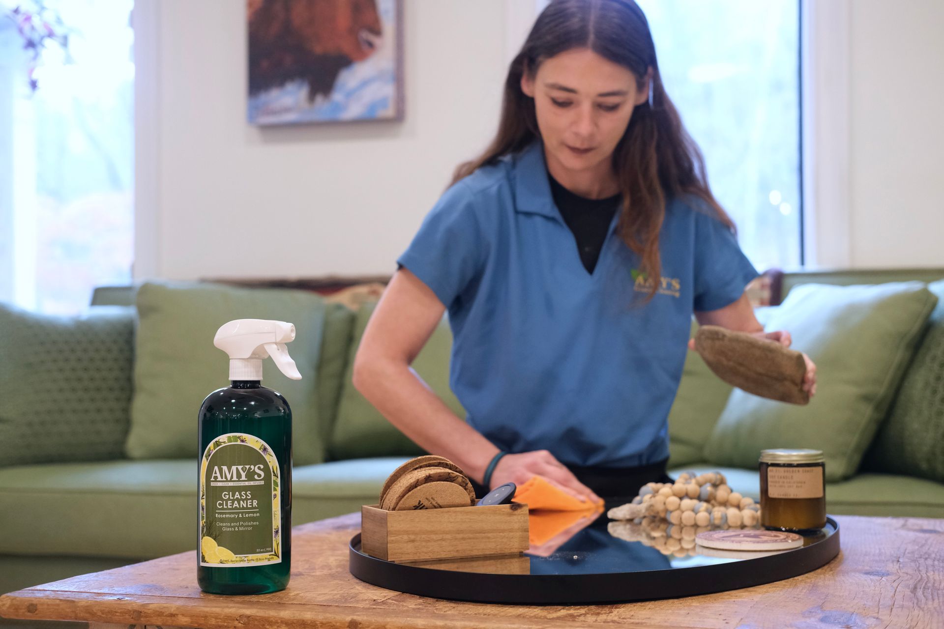 Woman in blue cleaning a tray of food on a table, with cleaning supplies visible.