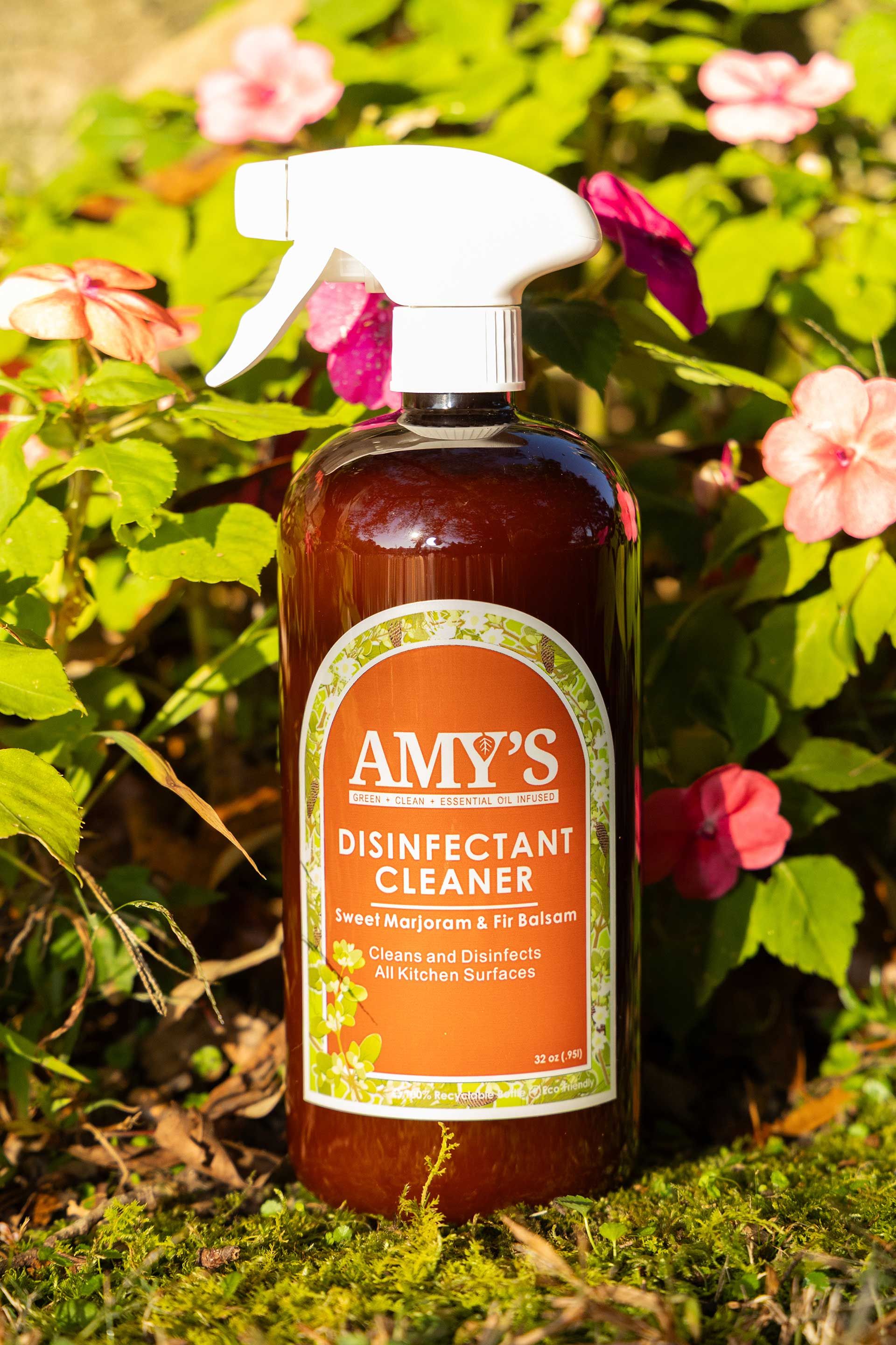 Amy's disinfectant cleaner spray bottle on a bed of green moss and flowers, outdoor setting