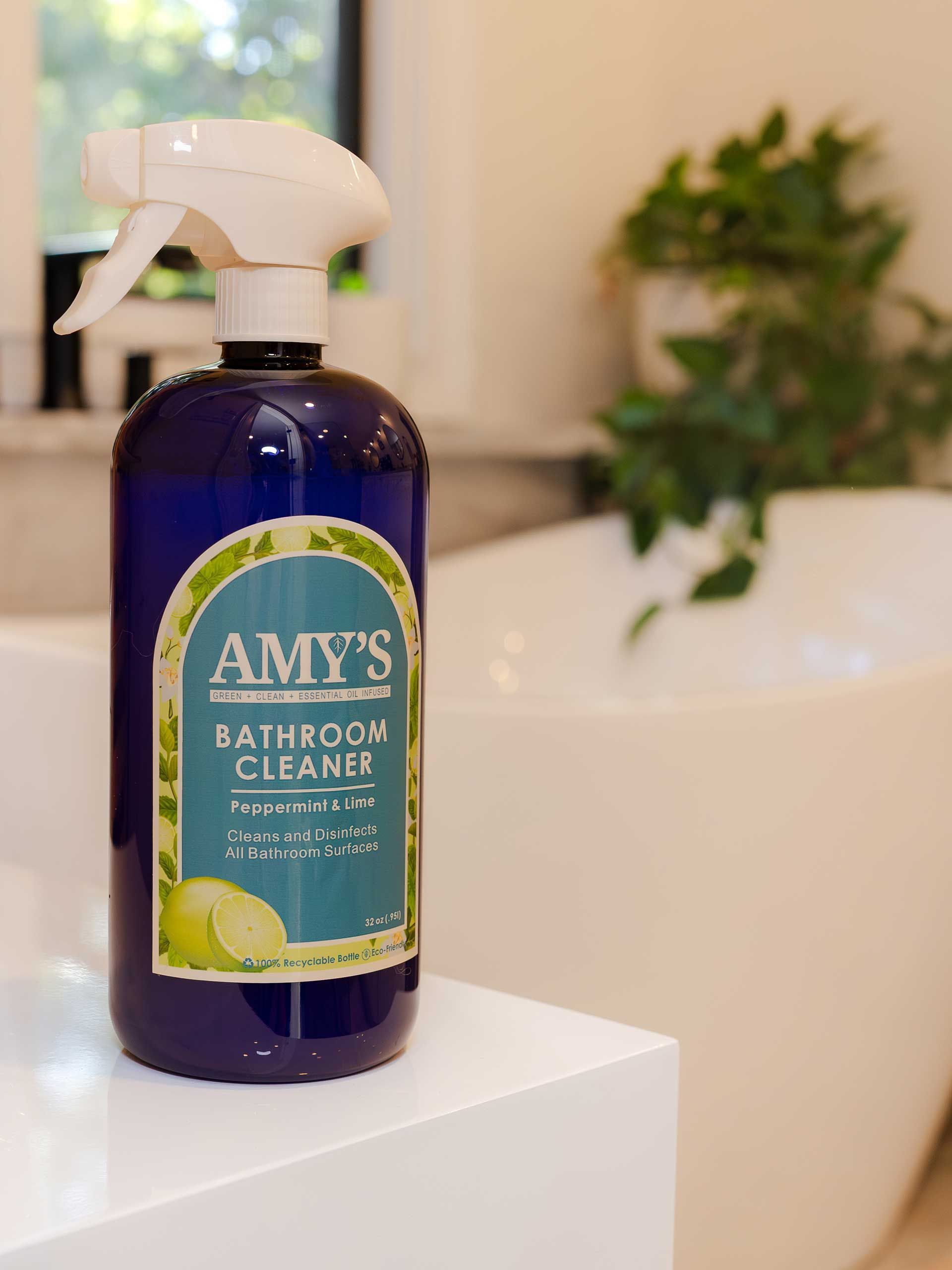 Amy's bathroom cleaner bottle with a blue bottle and lime graphic on a white shelf near a bathtub