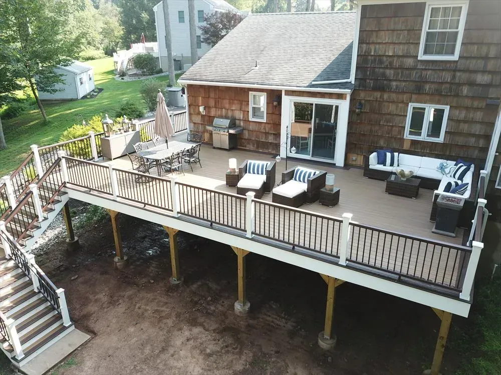 Elevated wooden deck with outdoor furniture and stairs leading down to a yard.