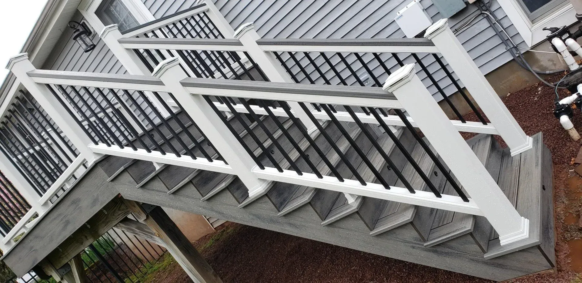 Exterior stairs with white railings and black balusters leading up to a deck.