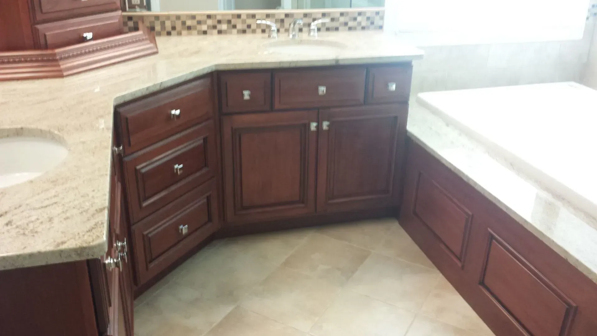 Bathroom with brown cabinets, beige countertops, and tile floors. Includes a sink and bathtub.