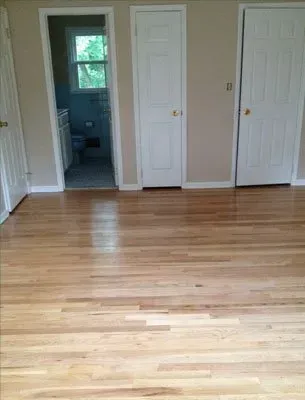 Hardwood floors in a room with beige walls, and three white doors.