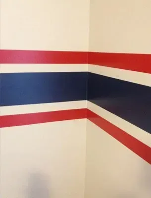 Red, white, and blue stripes painted on the corner of a white wall.