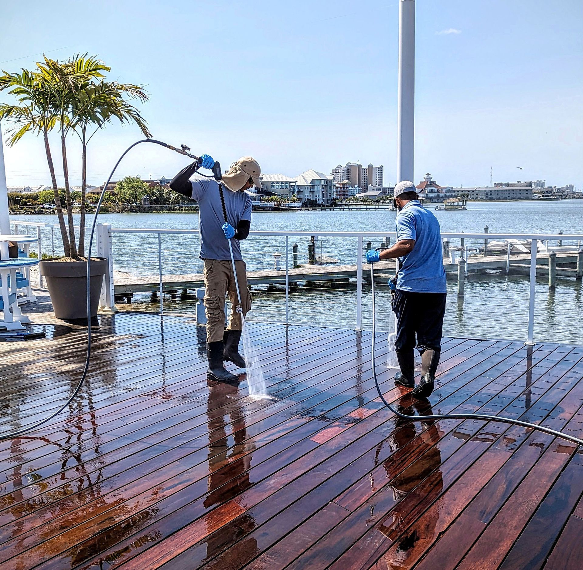 two men are cleaning a wooden deck near the water
