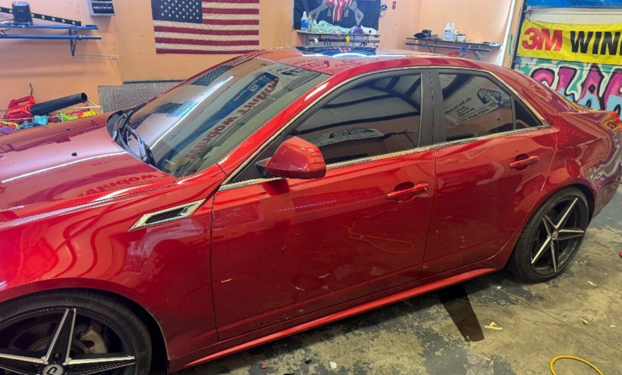 Red Cadillac CTS with tinted windows, parked indoors.