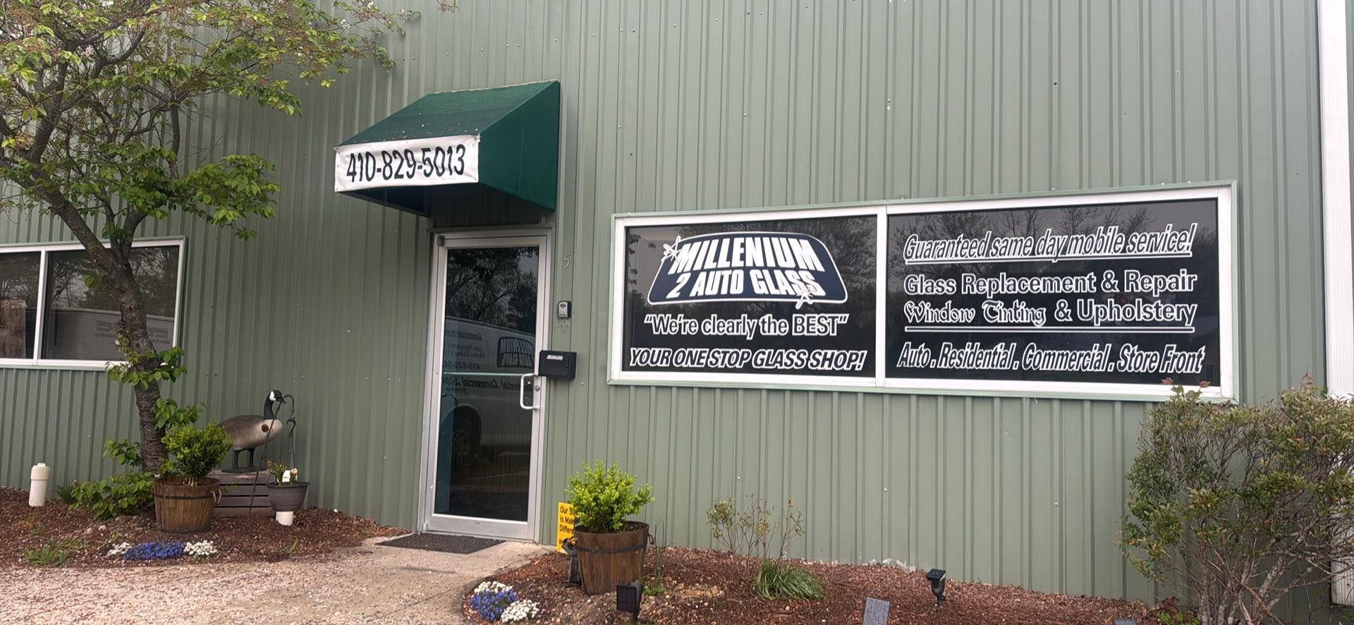 Building exterior with signs for upholstery and auto repair businesses. Green and white.
