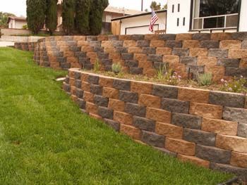 Tiered brick retaining wall beside a sloped green lawn in a residential yard