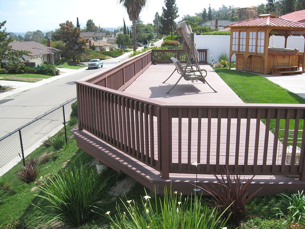 Backyard deck with brown railing, lounge chairs, and a gazebo beside a suburban street