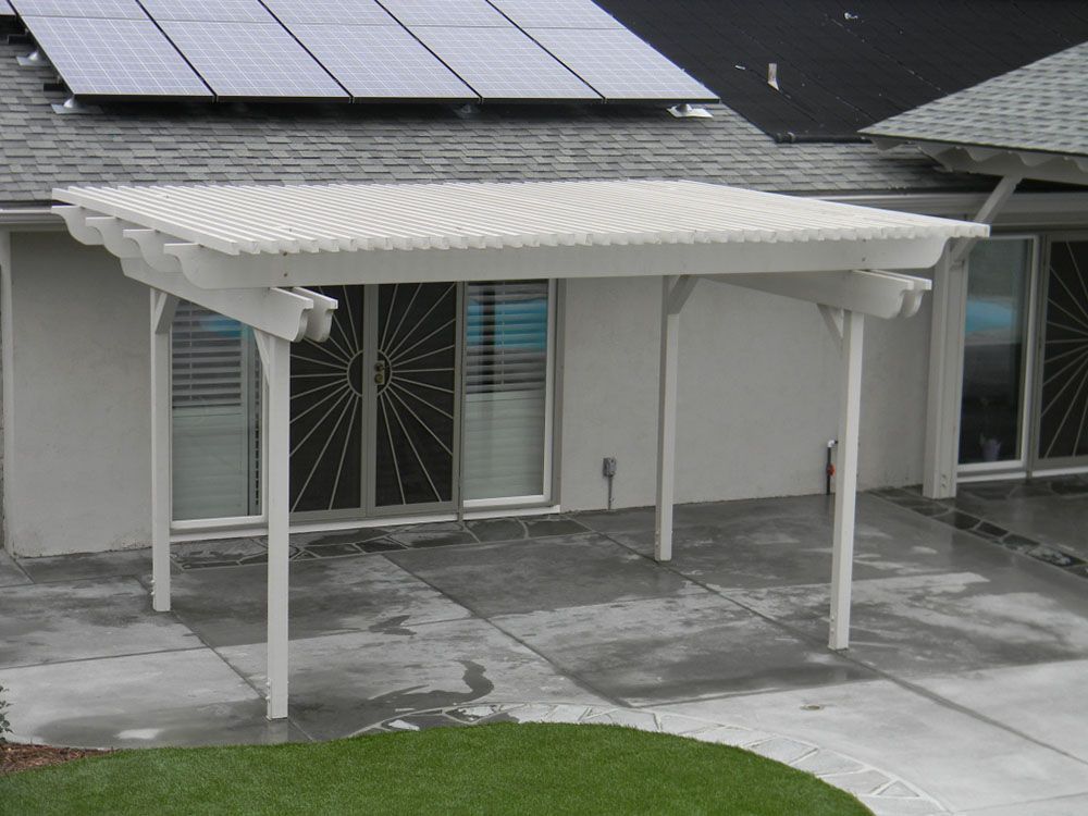 White patio awning over a concrete patio beside a house with solar panels on the roof