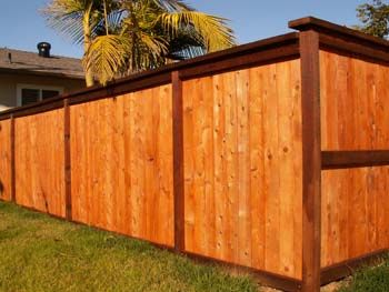 Wooden privacy fence with a brown top rail beside a grassy yard