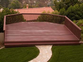 Large wooden backyard deck with brown railings and stone path leading to it