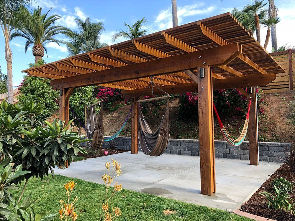 Wooden pergola with hanging hammocks on a stone patio in a tropical garden