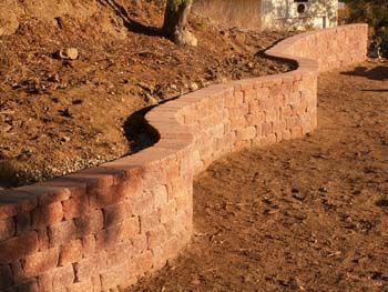Curved stone retaining wall lining a dry, dirt hillside path