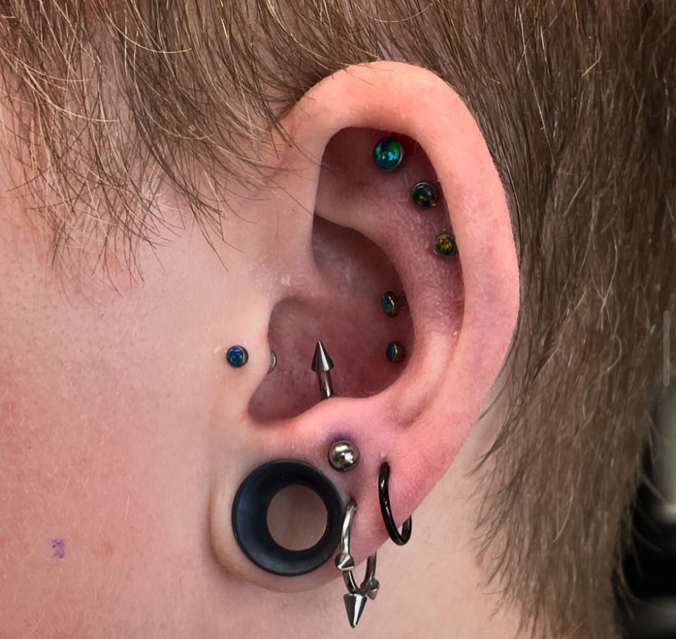 A close-up of a person's ear with multiple piercings